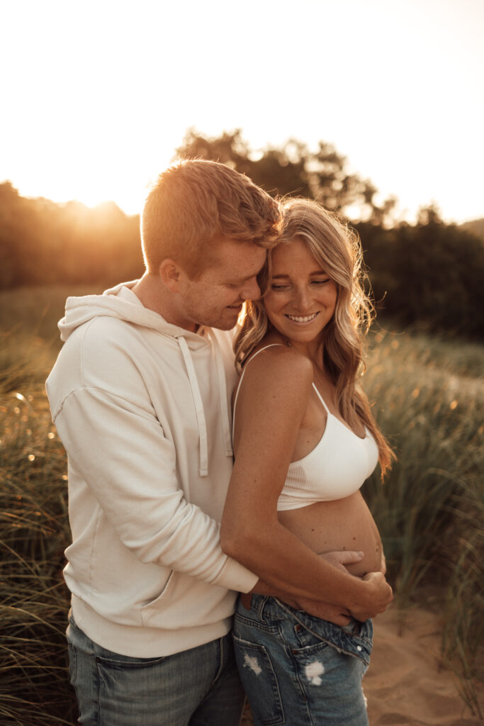 Dad holding pregnant mom's belly, both smiling