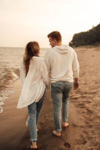 Husband and wife holding hands walking away from the camera on the beach