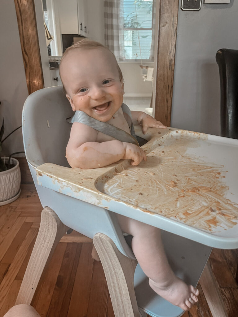 baby smiling in highchair with spaghetti sauce everywhere