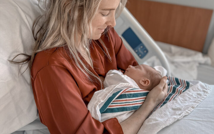 Mom in hospital bed looking at her newborn baby in her arms