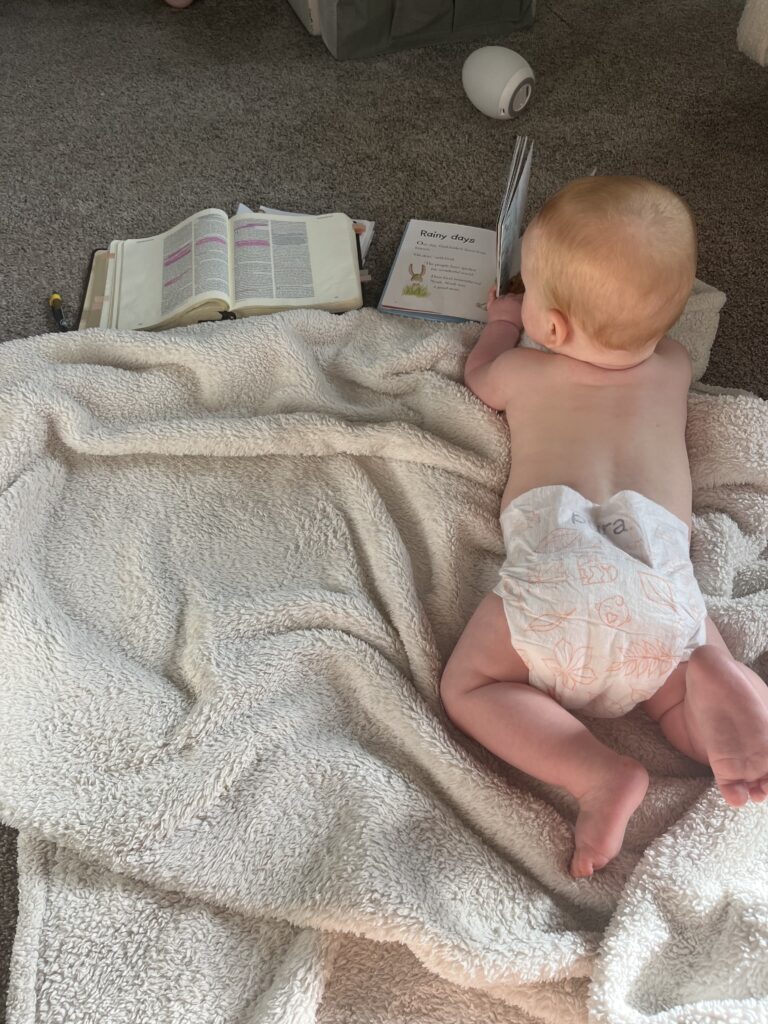 A baby laying on the ground reading the Bible 