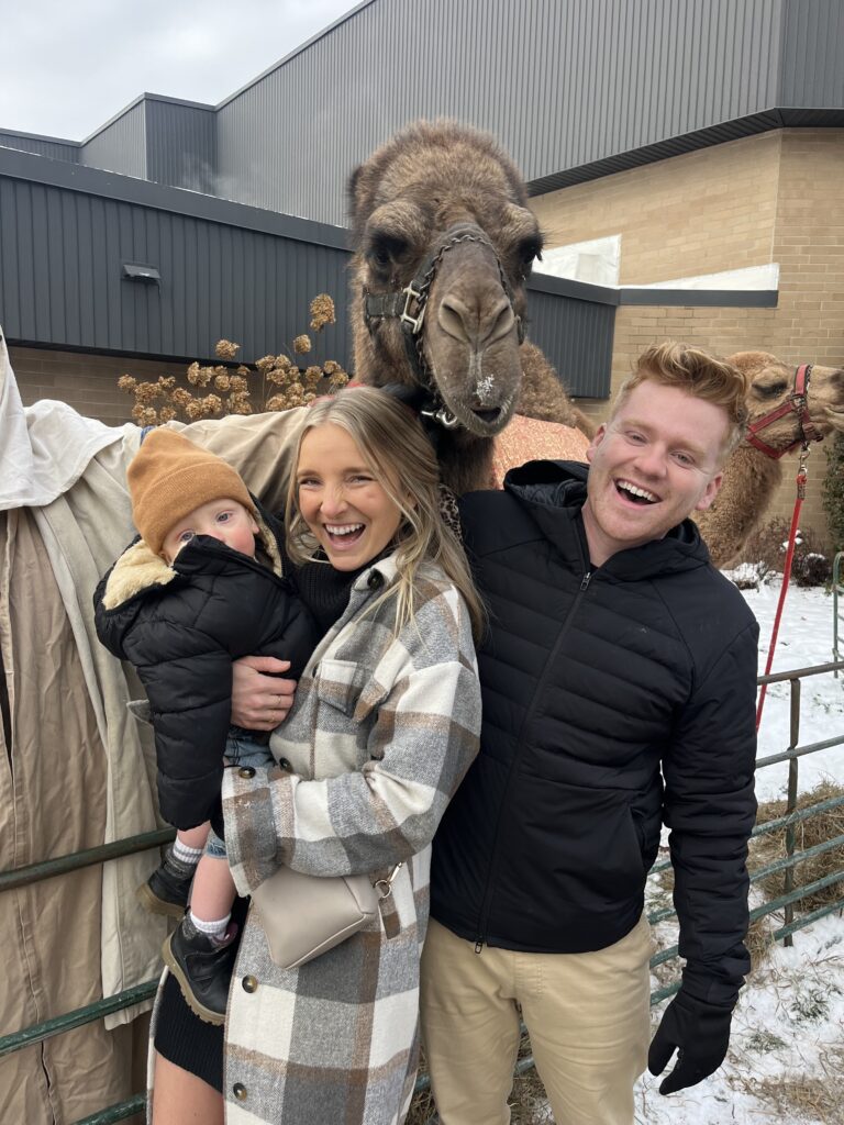 Mom, dad, and 1 year old son posing by a camel