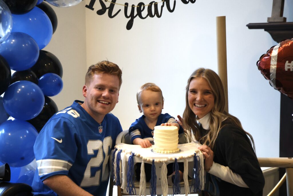 Mom, dad and 1 year old son posing with his smash cake, smiling 