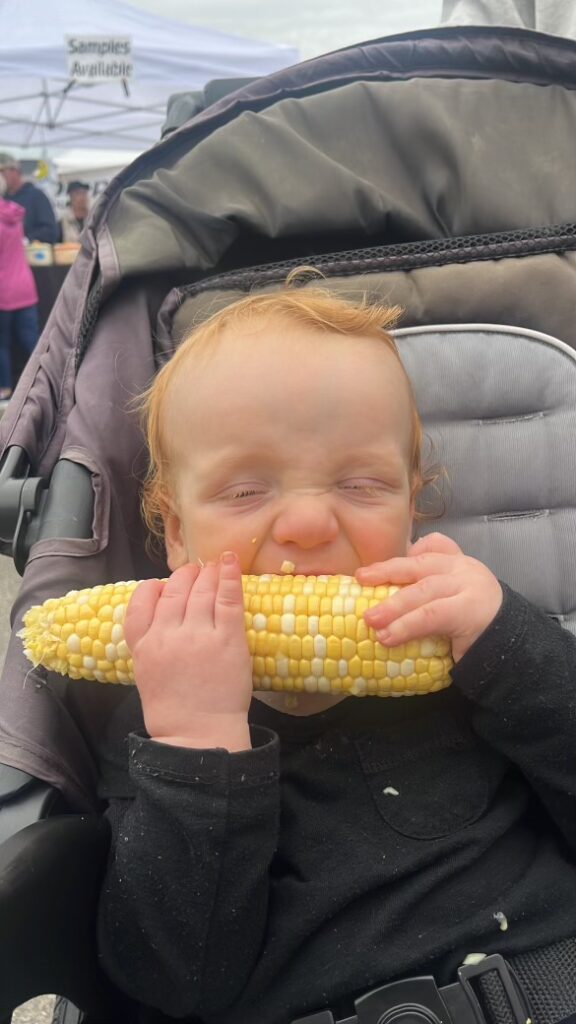 Nourishing foods for Toddler: one year old boy happily eating corn on the cob