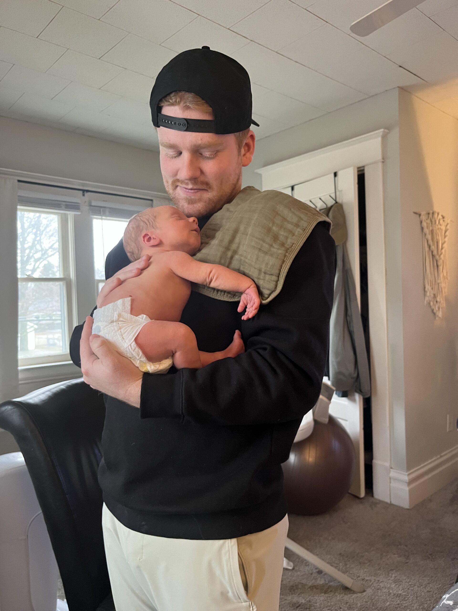 Dad holding new born baby smiling down at him