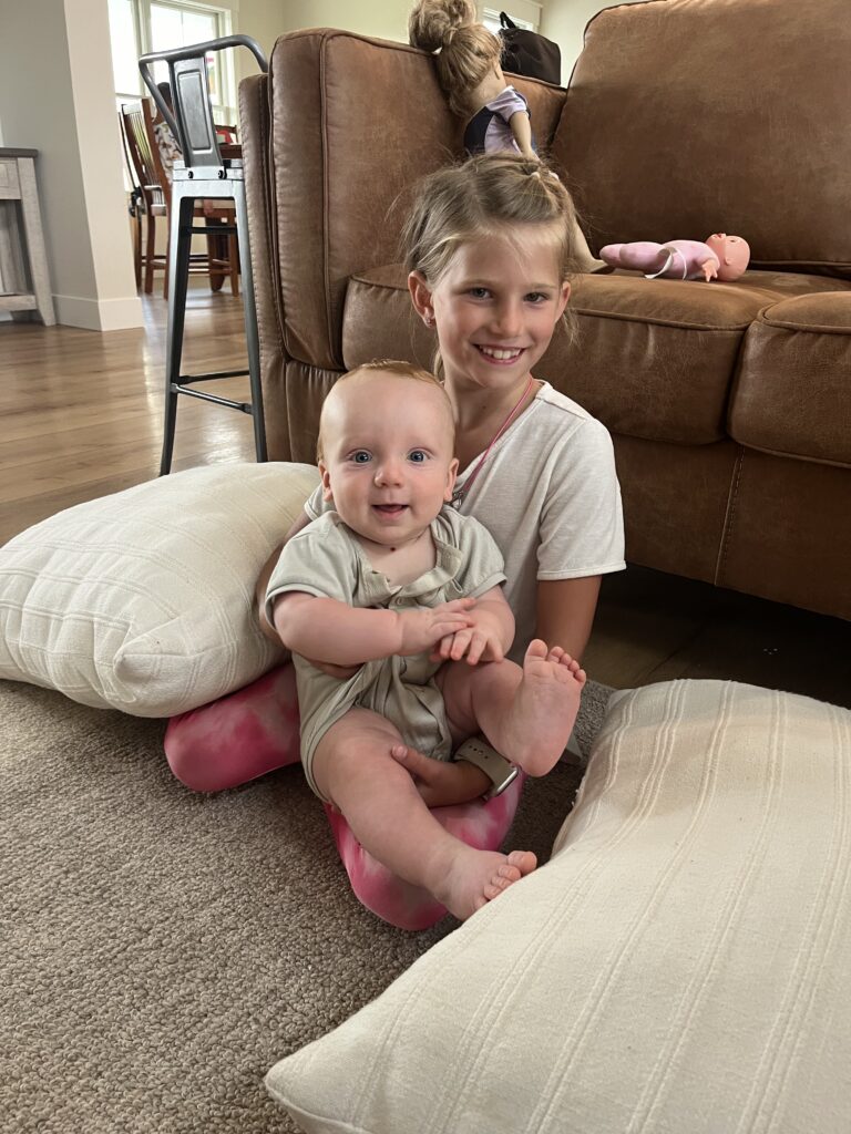 Cute girl holding a baby - both smiling at the camera