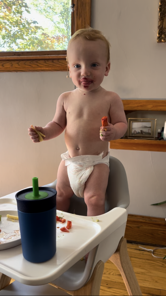 Nourishing foods for toddler: one year old boy standing in high chair 