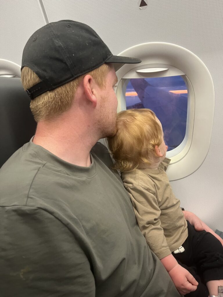 Dad and son looking out the window on a plane