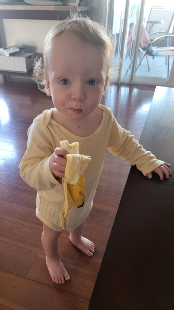 Nourishing foods for toddler: one year old boy eating a banana 