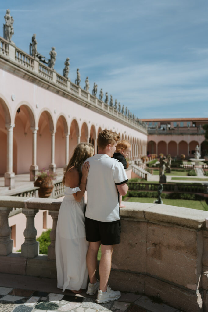 Mom and dad holding their 1 year old looking out over a balcony