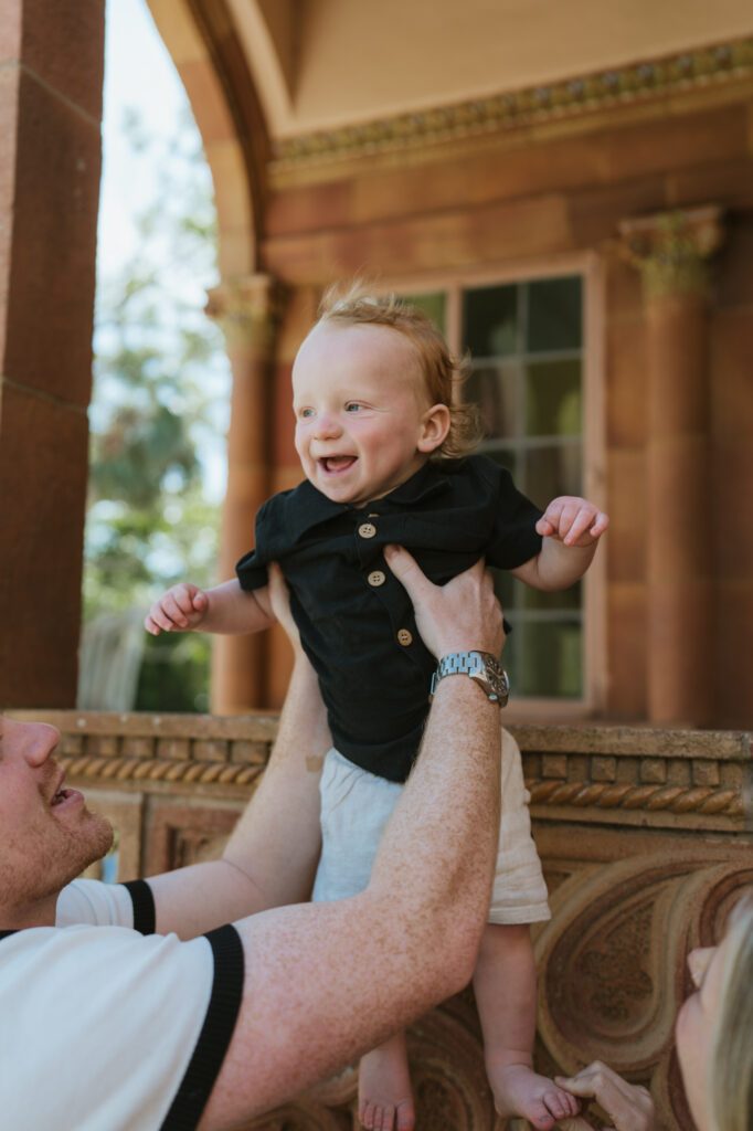 Cute baby being held in the air by his daddy
