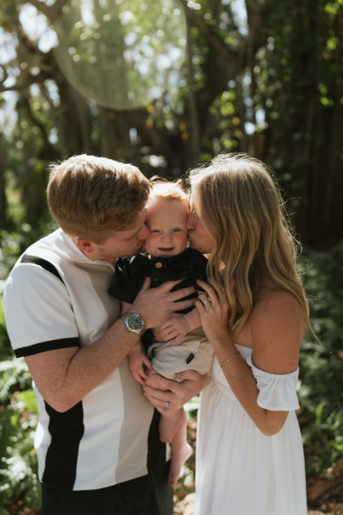 Mom and dad kissing their one year old son