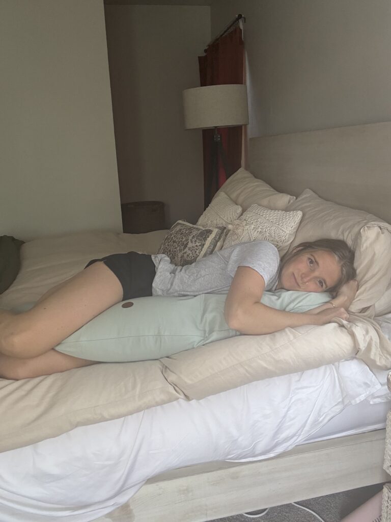 Mom laying in bed with her pregnancy pillow