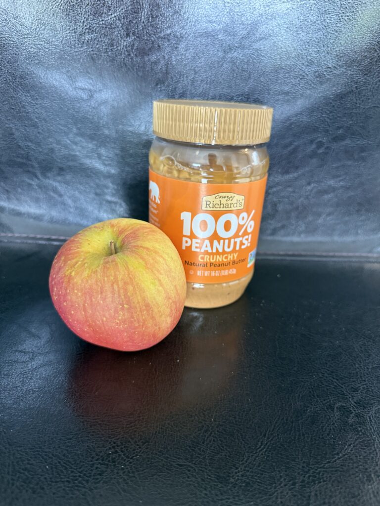 Apple and jar of natural crunchy peanut butter