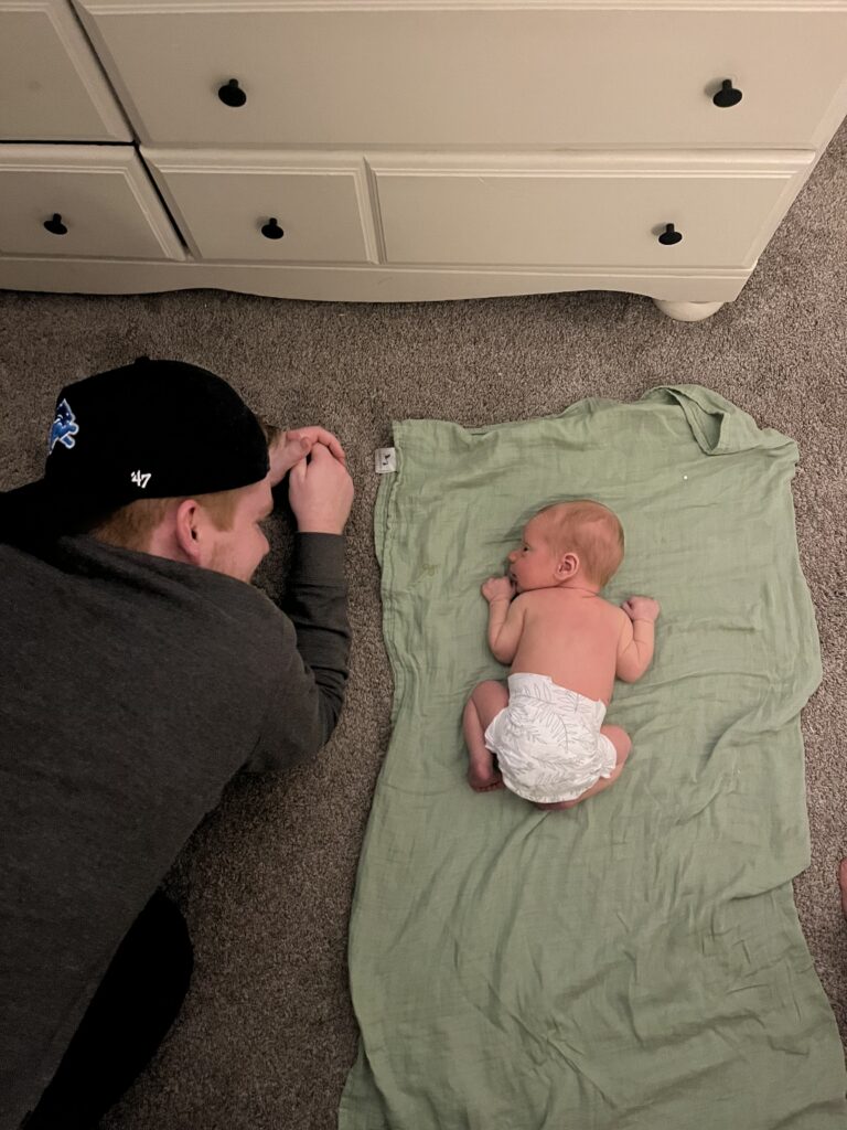 Dad and newborn doing tummy time together 