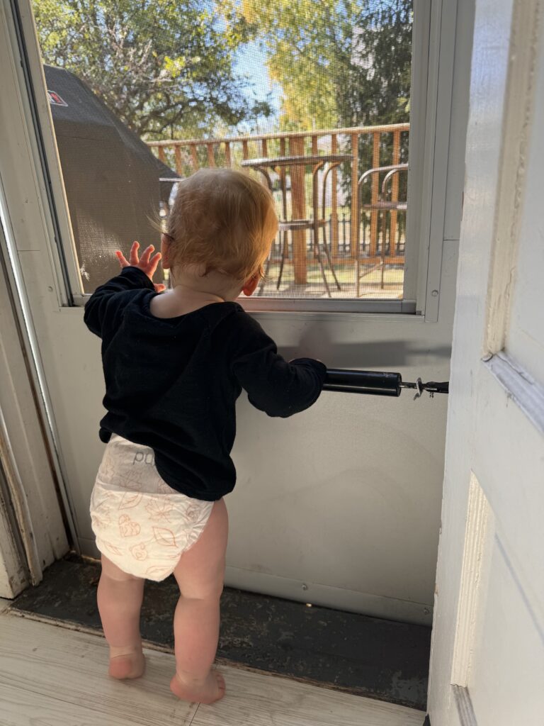Toddler looking out window in long sleeve and diaper